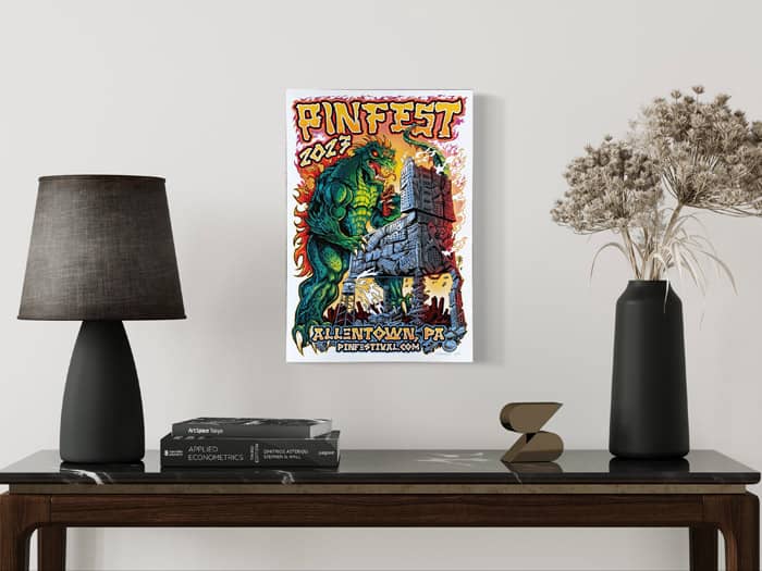 A 2023 Pinfest poster of an angry green Godzilla playing pinball on a destroyed city machine while holding and eating a building. 